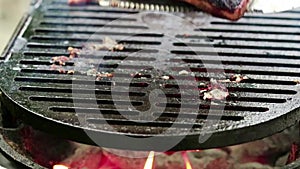 Fresh Salmon steak cooking on iron grates over flaming charcoal with skin side up gets flipped closeup