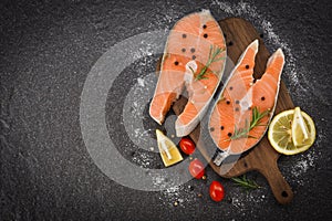 Fresh salmon steak with herbs and spices lemon rosemary tomato on wooden cutting board background - Raw salmon fish fillet and ice