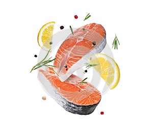 Fresh salmon steaks, spices and lemon slices falling on white background