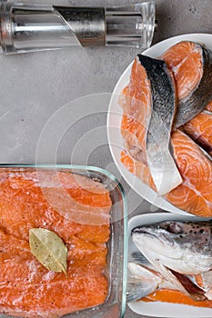 fresh Salmon or trout fish on cutting board with pepper, bay leaf, Red fish fillet, trimmings, fin, skin, fish scale, head, steaks