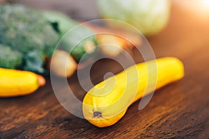 Fresh salubrious colourful vegetables on wooden background, squash in focus, potatoes, carrots, broccoli, zucchini unfocused,