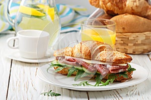 Fresh sandwich-croissant with ham, arugula, cucumber and cheese