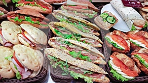 Fresh sandwiches with dried ham on a bed of tomatoes, lettuce and fresh cucumber
