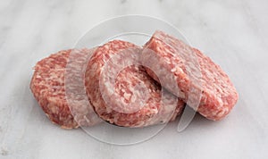 Fresh sausage patties on a marble cutting board photo