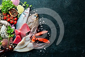 Fresh seafood and fish on black stone background. Flounder, lobster, squid, tuna, fish. Top view.