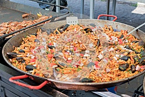 Fresh seafood penne tomato pasta cooking in large wok pan during hotel brunch buffet outside