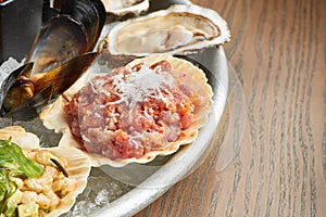 Fresh seafood - stuffed scallops or scallop tartare in a shell on ice. Film effect during post. Soft focus
