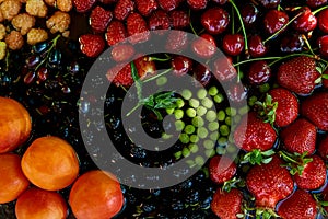 Fresh seasonal fruits and berries: strawberries, apricots, cherries, mulberry, raspberry under natural light. Healthy