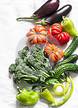 Fresh seasonal vegetables food background. Aubergines, tomatoes, peppers, broccoli on a light background, top view. Flat lay, copy