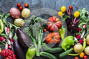 Fresh seasonal vegetables food background. Aubergines, tomatoes, radishes, peppers, broccoli, potatoes, beets on a dark background