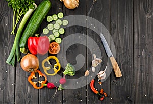 Fresh seasonal vegetables and knife on wooden table background