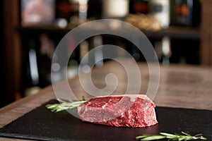 Fresh, seasoned, organic juicy unprepared striploin steak on a wooden background in a restaurant interior. Barbecue meat.