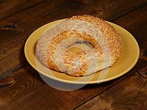 Fresh sesame bagel on a yellow plate on a wooden table