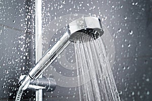 Fresh shower behind wet glass window with water drops splashing.