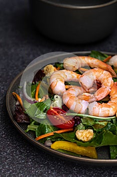 Fresh shrimp and greens salad on dark background