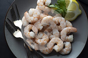 Fresh shrimps in plate over dark background. Healthy food. Top view. Copy space