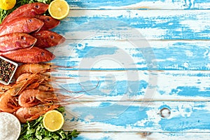 Fresh shrimps and red mullet fish on blue wooden background