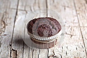 Fresh single dark chocolate muffin on rustic wooden table