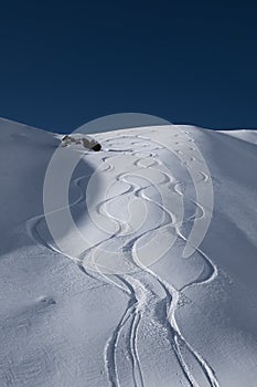 Fresh ski tracks leading down from alpine mountain ridge