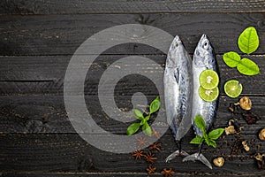 Fresh skipjack tuna fish on dark black wooden background, Fish with spices and vegetables, cooking background concept