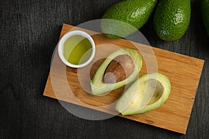Fresh sliced avocado and olive oil on wooden background. Cosmetic oils, body and face care. Avocado oil ingredients.
