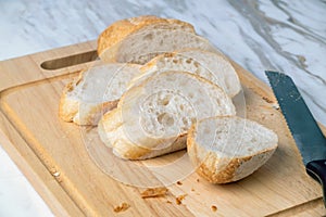 Fresh sliced baguette bread on marble table.