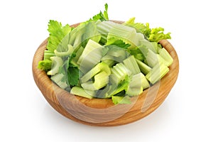 Fresh sliced celery in a wooden bowl isolated on white background.