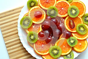 Fresh sliced fruits on a plate wood table top view background