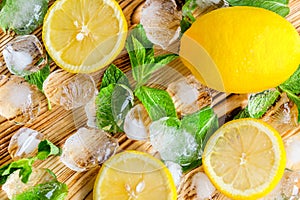 Fresh sliced lemon, bright green mint and ice on a wooden table. A non-alcoholic Mojito cocktail ingridients. Refreshment concept