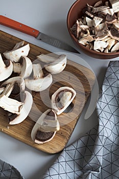 Fresh sliced mushrooms at wooden cutting board. Chopping food ingredients. Food background of fresh champignons