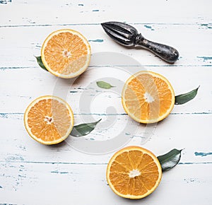 Fresh sliced oranges with leaves and wooden crush for fruit, rustic wooden background, top view