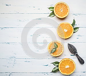 Fresh sliced oranges with leaves and wooden crush for fruit, on rustic wooden background, view, space for text