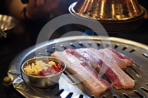 Fresh sliced pork on hot pan and chili garlic with range hood smoke Korean-Style BBQ in a Korean restaurant