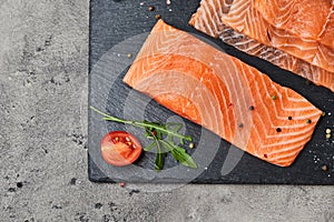 Fresh sliced salmon fillet with arugula, avocado and lemon on slate plate. Wild atlantic fish