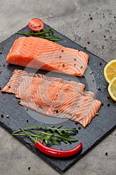 Fresh sliced salmon fillet with arugula, avocado and lemon on slate plate. Wild atlantic fish