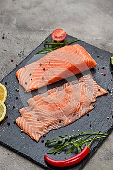 Fresh sliced salmon fillet with arugula, avocado and lemon on slate plate. Wild atlantic fish