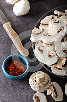 Fresh sliced white mushrooms on kitchen table with spice