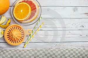 Fresh slices citrus fruit and orange manual juicer on light wooden table. Top view. With copy space