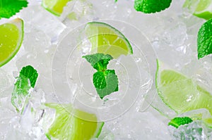 Fresh slices of green limes and mint over crushed ice cubes