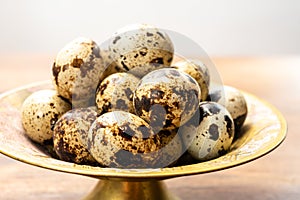Fresh small spotted partridge eggs on bronze plate