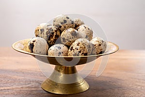 Fresh small spotted partridge eggs on bronze plate