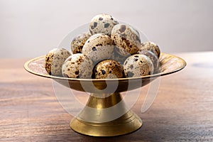 Fresh small spotted partridge eggs on bronze plate