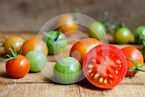 Fresh small tomatoes with green stem on wooden background