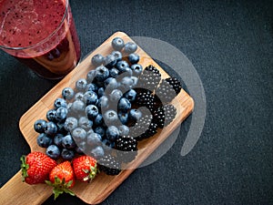 Fresh smothie made with blueberries, strawberries and blackberries with some forest fruits on a table