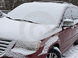 Fresh snow and snowflakes on the top of red car windows after early December snowfall