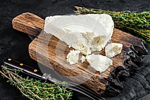 Fresh Soft goat cheese on a cutting board with thyme. Black background. Top view