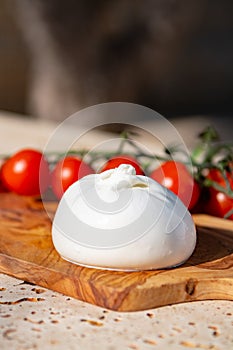 Fresh soft white burrata, buttery cheese, made from a mix of mozzarella and cream, original from Apulia region, Italy with tomato