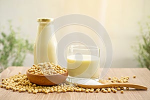 Fresh soybean seeds in brown wooden bowl, sugar in a spoon and two bottles of soy milk on the table,  under sunlight morning