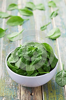 Fresh spinach leaves in bowl on rustic kitchen table