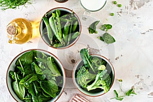 Fresh spinach leaves, green peas, broccoli in a bowl, top view